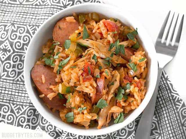 Top view of a bowl of Slow Cooker Jambalaya sitting on a patterned napkin with a fork on the side 