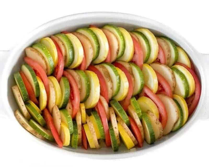 Sliced veggies in a white baking dish.