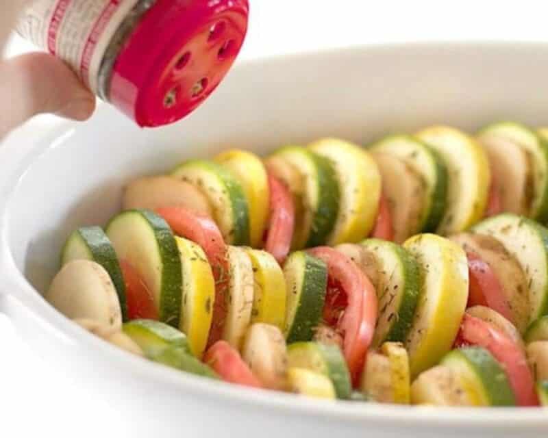 Sprinkling the vegetables with salt, pepper, and thyme. 