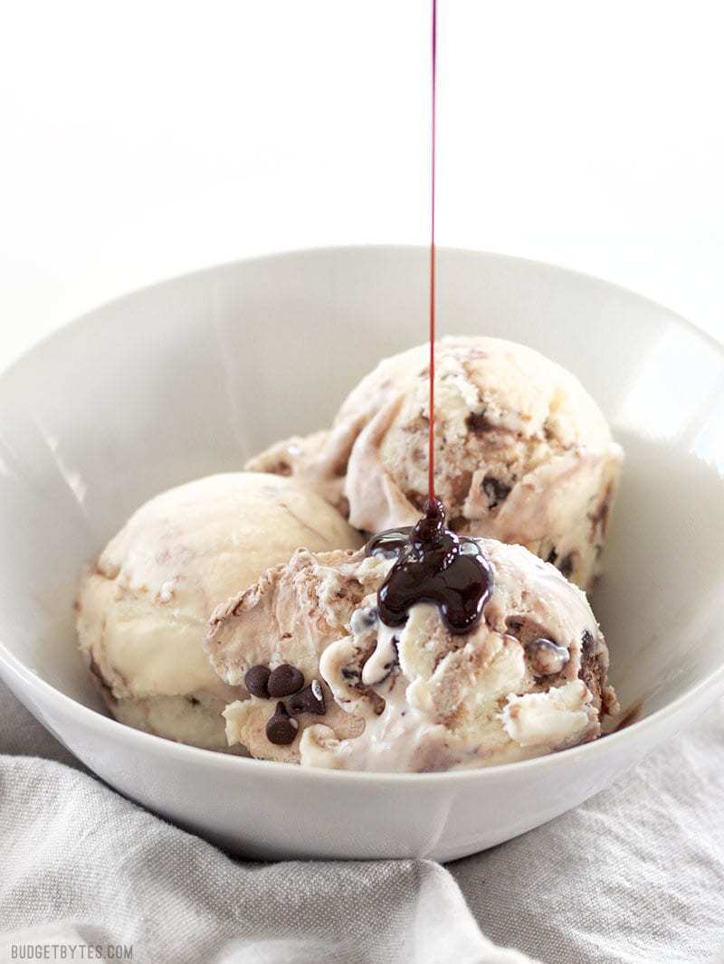 Chocolate syrup being poured onto a bowl of No-Churn Mint Chocolate Chip Ice Cream