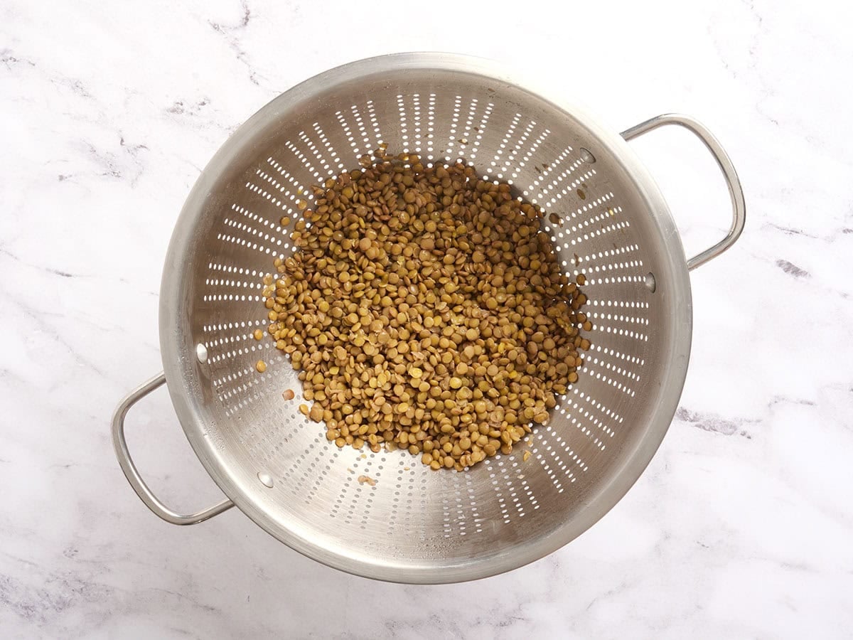 Cooked brown lentils in a colander.