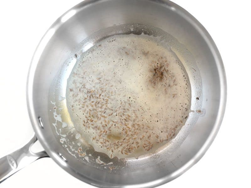 Cumin seeds sizzling in butter in a sauce pot