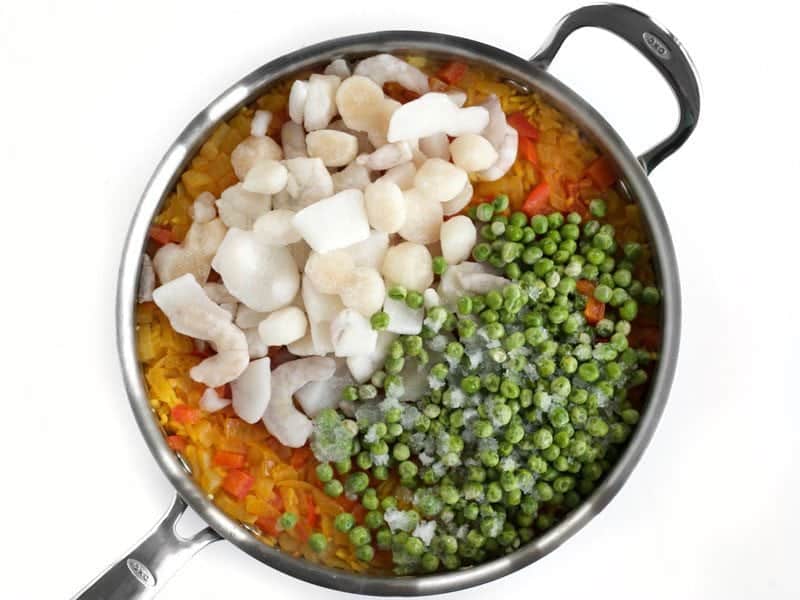 Cooked Rice with Frozen Seafood and Peas added on top in skillet