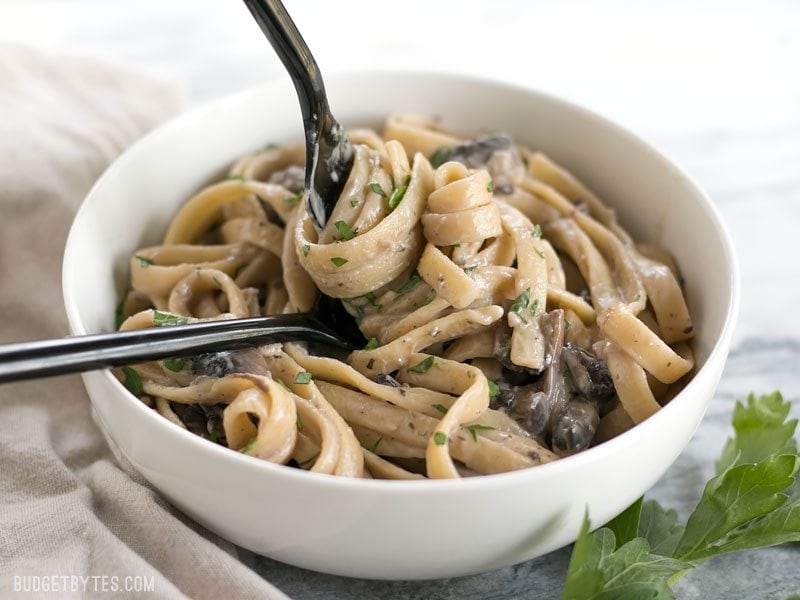 A bowl of Creamy Mushroom Herb Pasta with a fork twirling the pasta in a spoon.