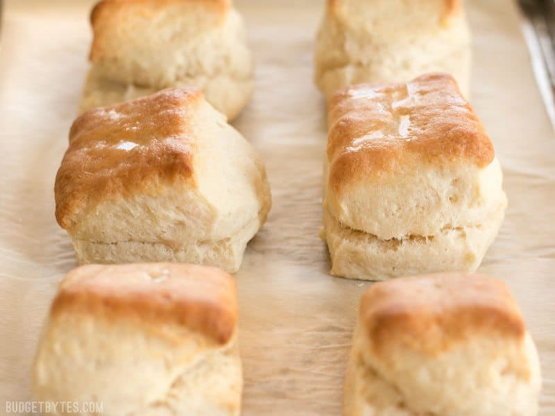 Side view of freshly baked Freezer Biscuits on a parchment lined baking sheet