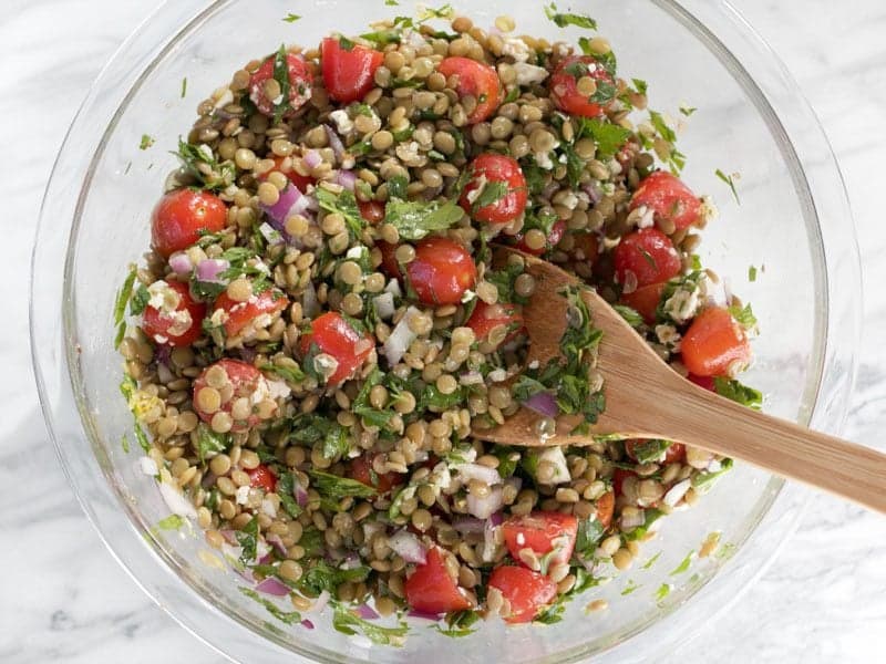 Mixed Marinated Lentil Salad in a glass bowl with a wooden spoon