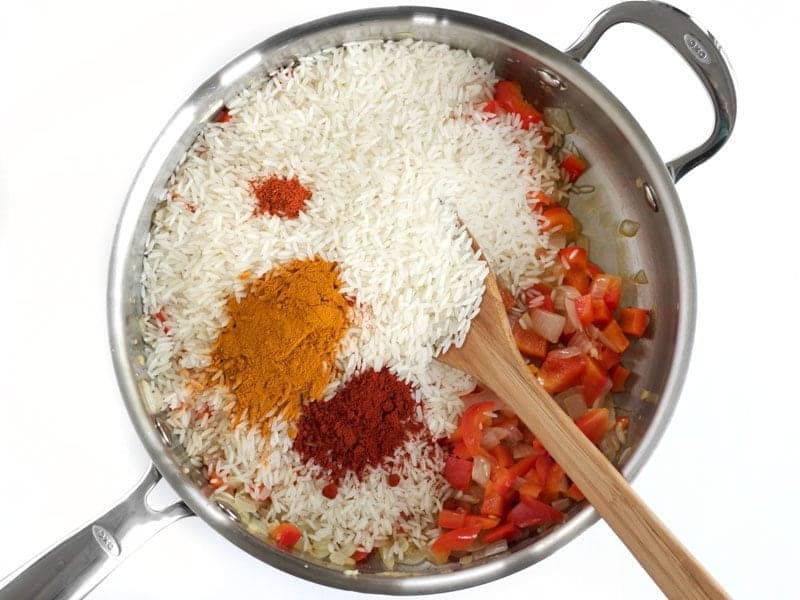 Rice and Spices added to skillet with bell pepper and onion