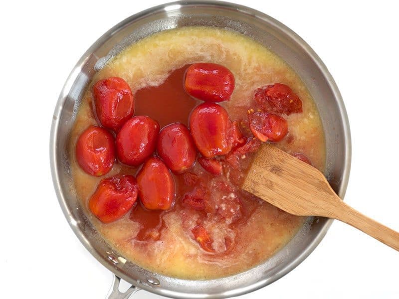 Add Whole Peeled Tomatoes to the skillet, break them up into pieces