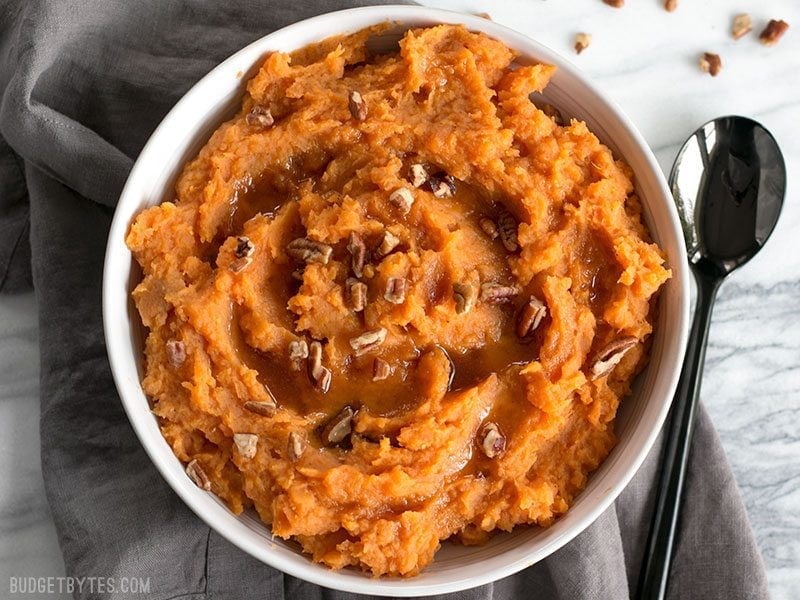 A bowl full of Maple Brown Butter Mashed Sweet Potatoes with pecans.