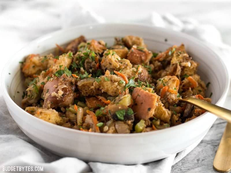 Front view of a bowl of Savory Vegetable Stuffing with a gold fork