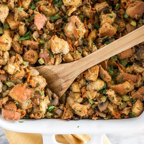 Overhead view of vegetarian stuffing in the casserole dish with a wooden spoon.