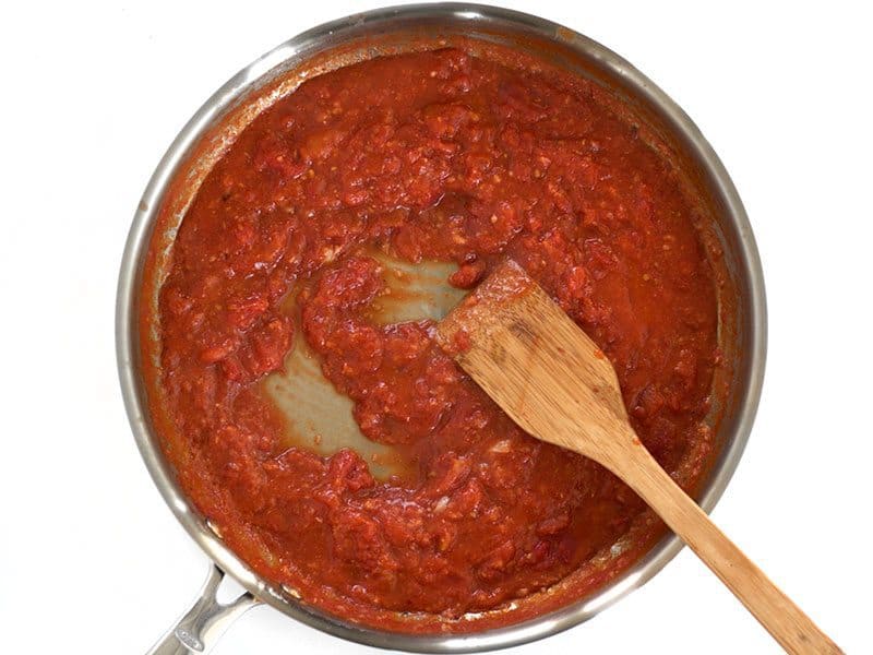 Simmered sauce in the skillet with a wooden spatula