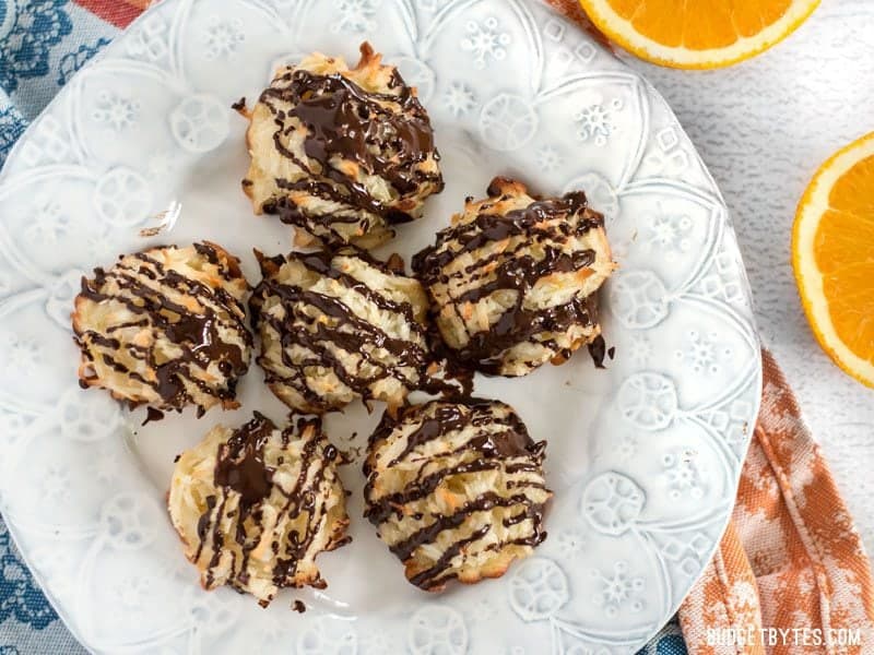Six Chocolate Glazed Macaroons on a plate, viewed from above, with fresh oranges on the side