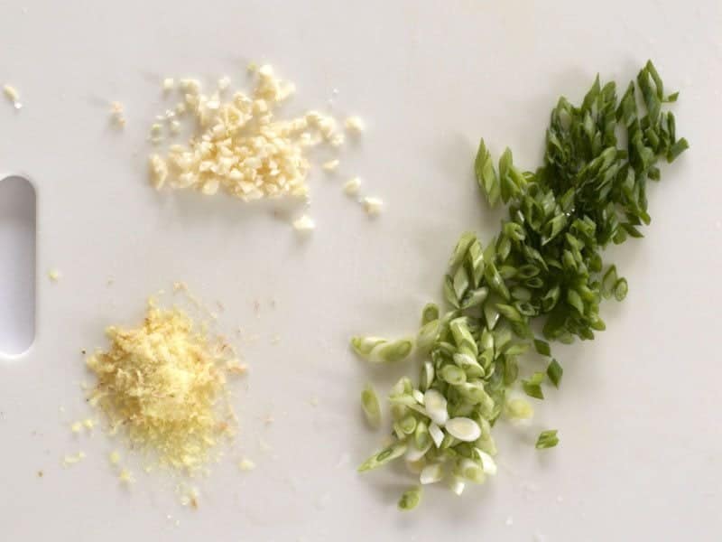 Minced Garlic, Grated Ginger, and sliced Green Onions on a cutting board