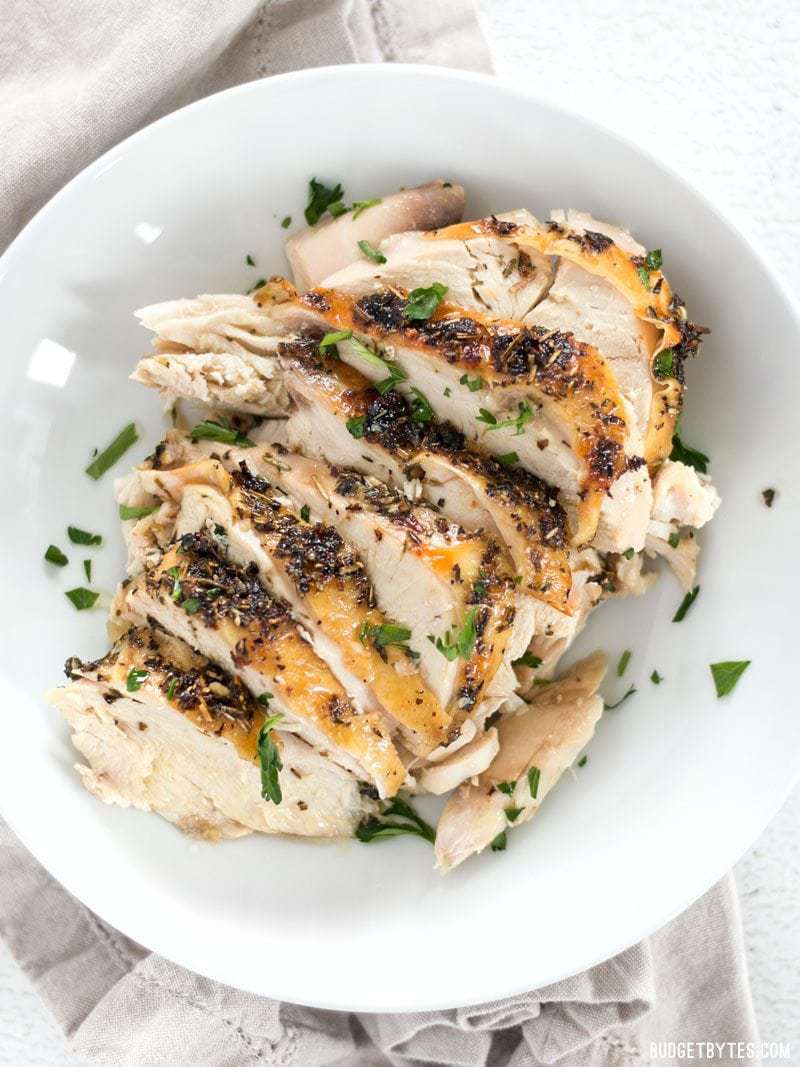 Sliced Herb Roasted Chicken Breast in a bowl, garnished with fresh parsley