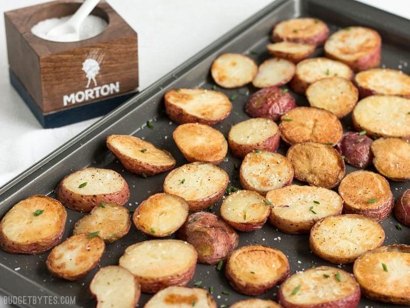 Salt & Vinegar Roasted Potatoes on a baking sheet with a small bowl of salt on the side 