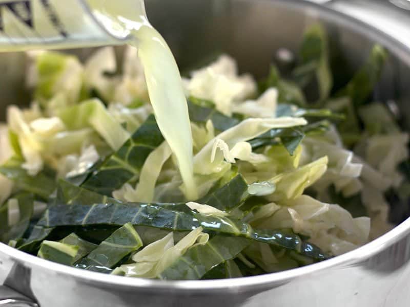 Chicken broth being poured over cabbage in the stock pot