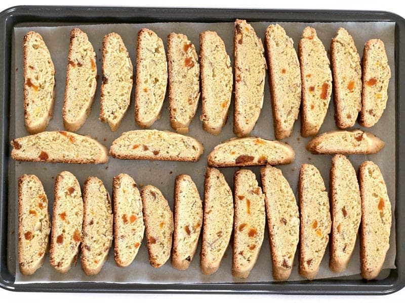 Biscotti slices laying on their side on the parchment lined baking sheet, ready for the second bake