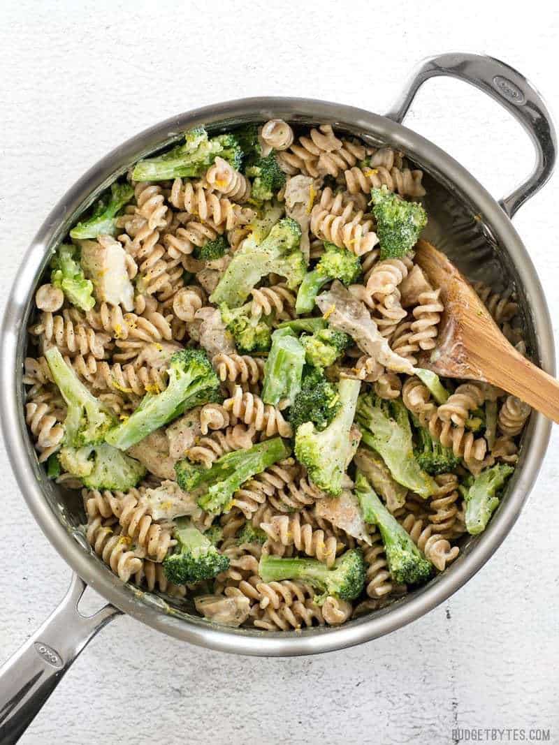 Finished Chicken and Broccoli Pasta with Lemon Cream Sauce in the skillet with a wooden spoon