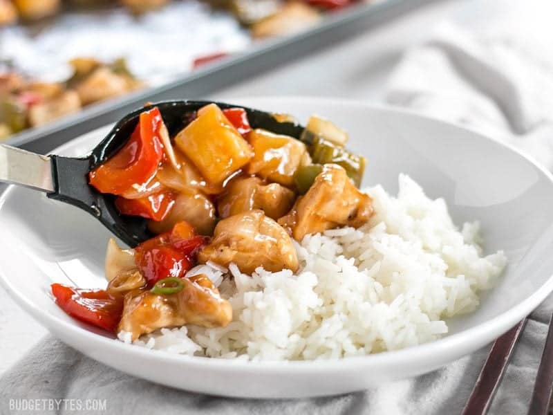 Sweet and Sour Chicken being spooned over a bowl of rice