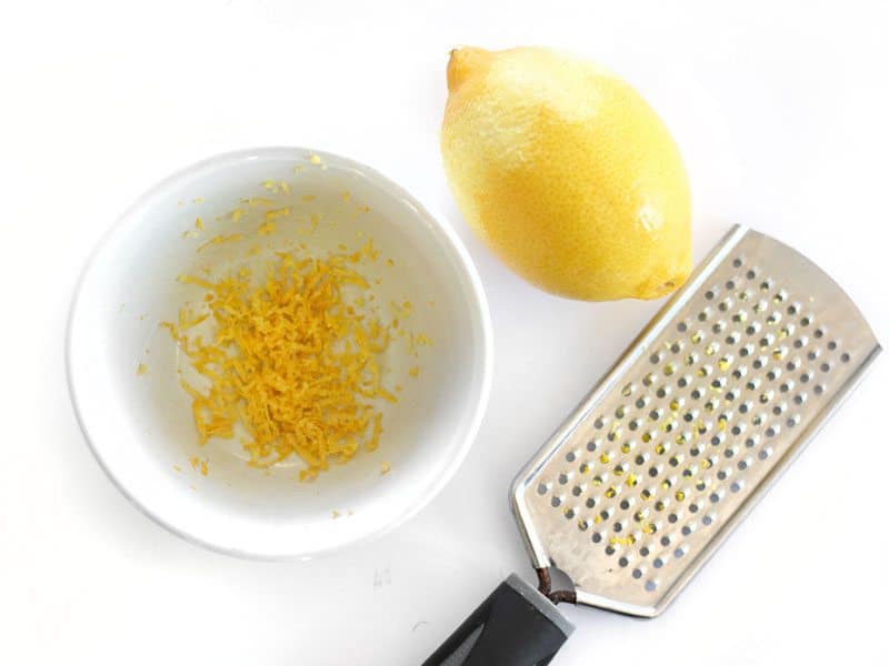 Zested Lemon, zest in the bowl, microplane next to the bowl
