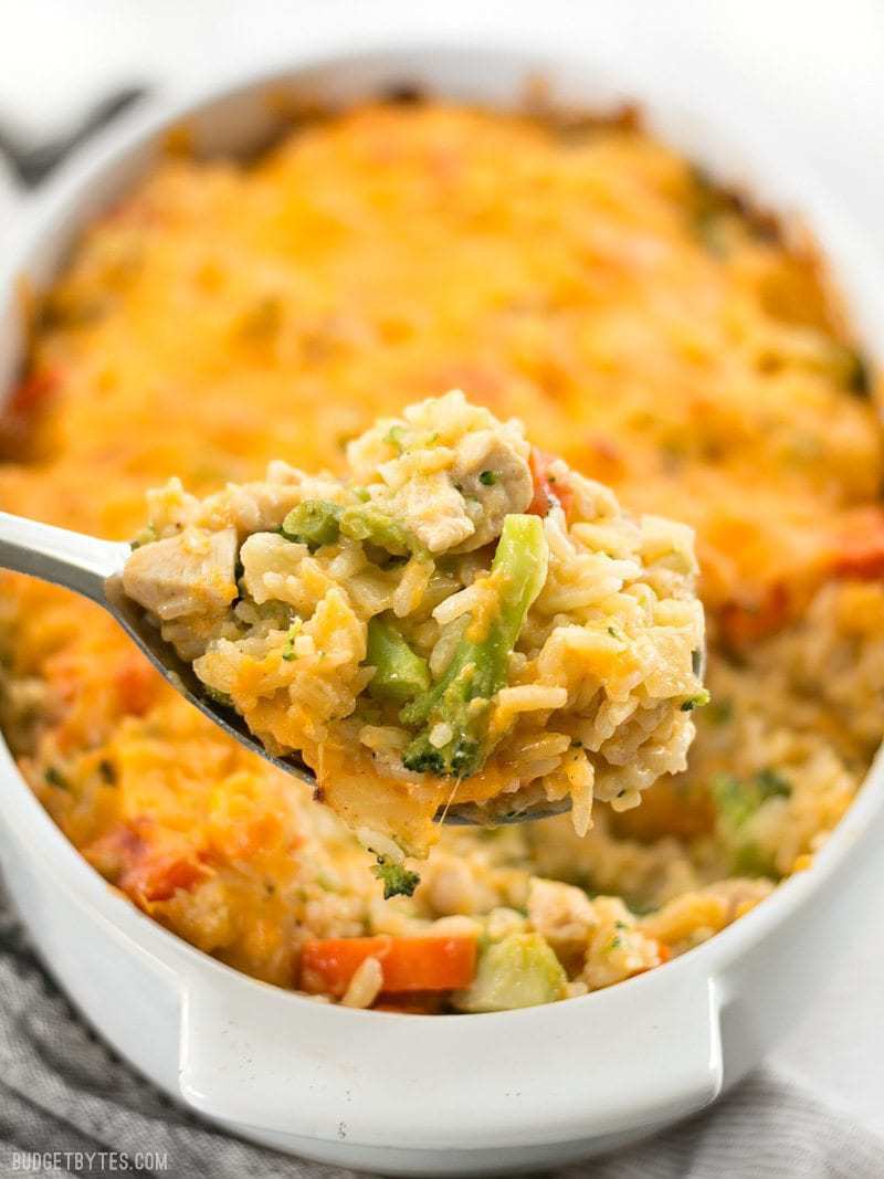 Front view of Cheesy Chicken Vegetable and Rice Casserole being scooped out of the casserole dish