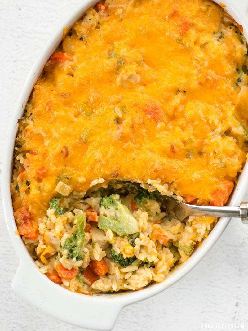 Overhead view of Cheesy Chicken Vegetable and Rice Casserole being scooped out of the casserole dish