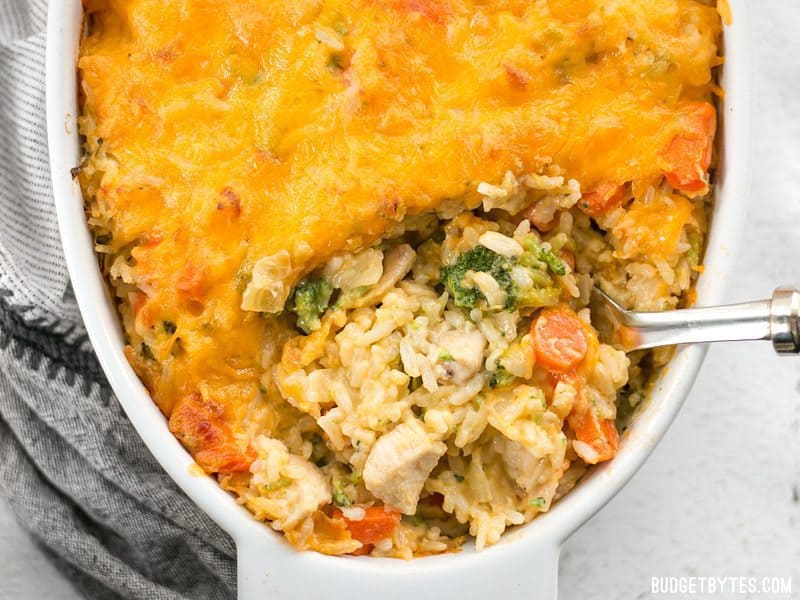 Close up of Cheesy Chicken Vegetable and Rice Casserole being scooped out of the casserole dish