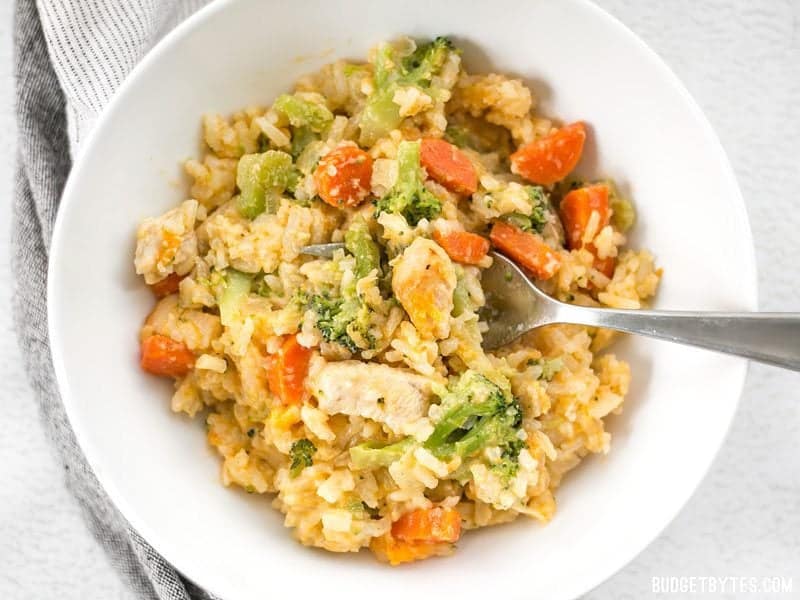 A bowl full of Cheesy Chicken Vegetable and Rice Casserole with a fork