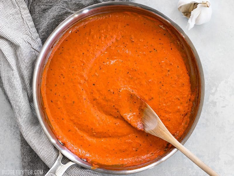 Creamy Roasted Red Pepper Sauce in a skillet with a wooden spoon