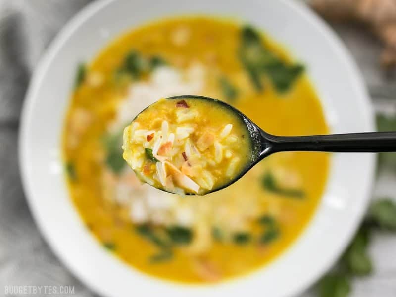 Close up of a spoonful of Golden Coconut Lentil Soup with the bowl in the background.