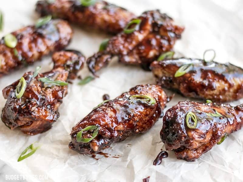 Front view of Raspberry Balsamic Baked Chicken Wings on parchment with sliced green onions