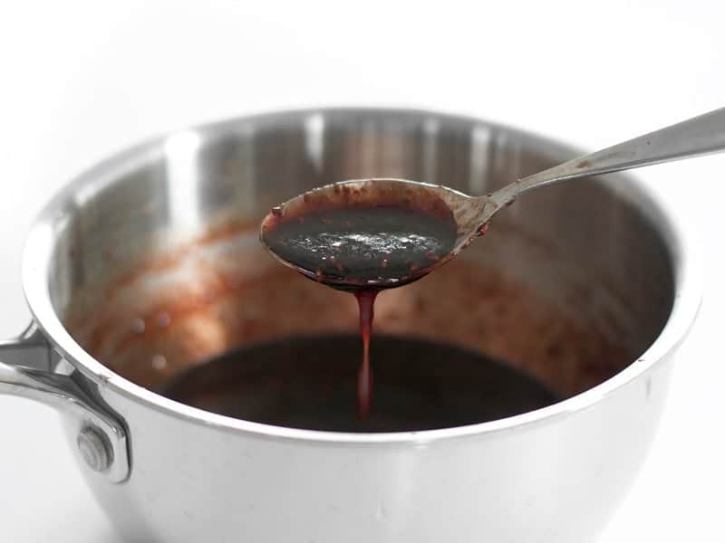 Raspberry Balsamic Glaze dripping off a spoon into the pot