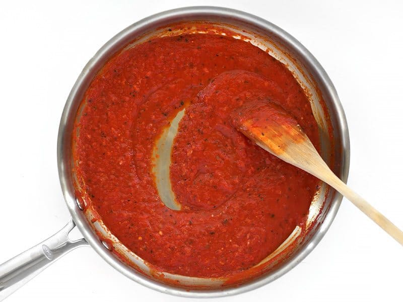 Simmered Roasted Red Pepper Sauce in the skillet with a wooden spoon