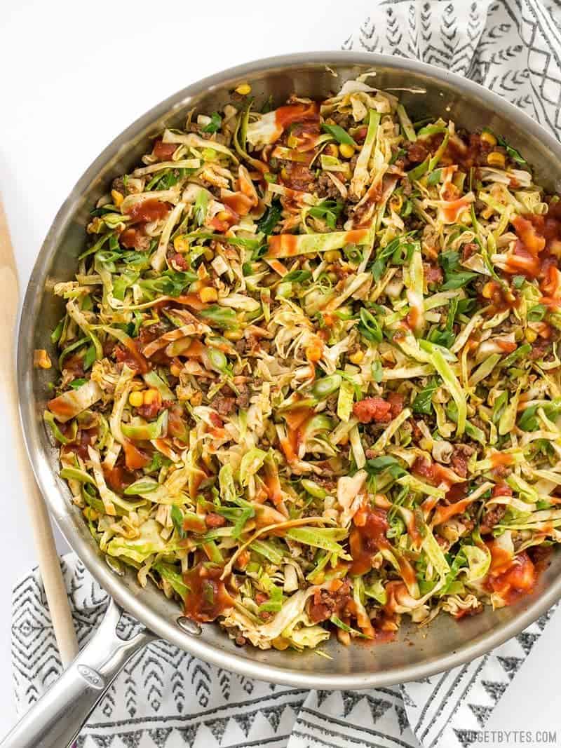 A skillet full of Southwest Beef and Cabbage Stir Fry with taco sauce drizzled over top
