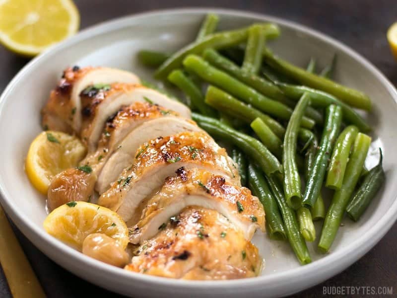 Front view of sliced Lemon Garlic Roasted Chicken on a plate with green beans