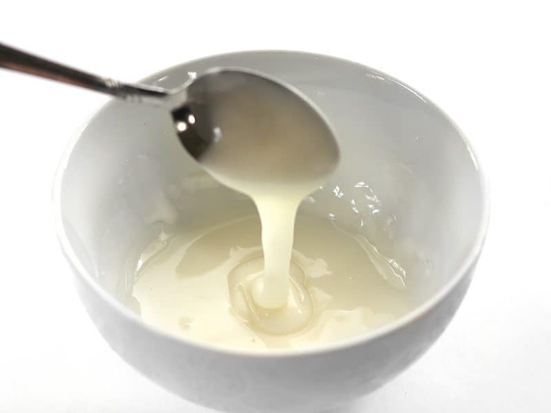 Lemon Icing drizzling off a spoon into a small bowl