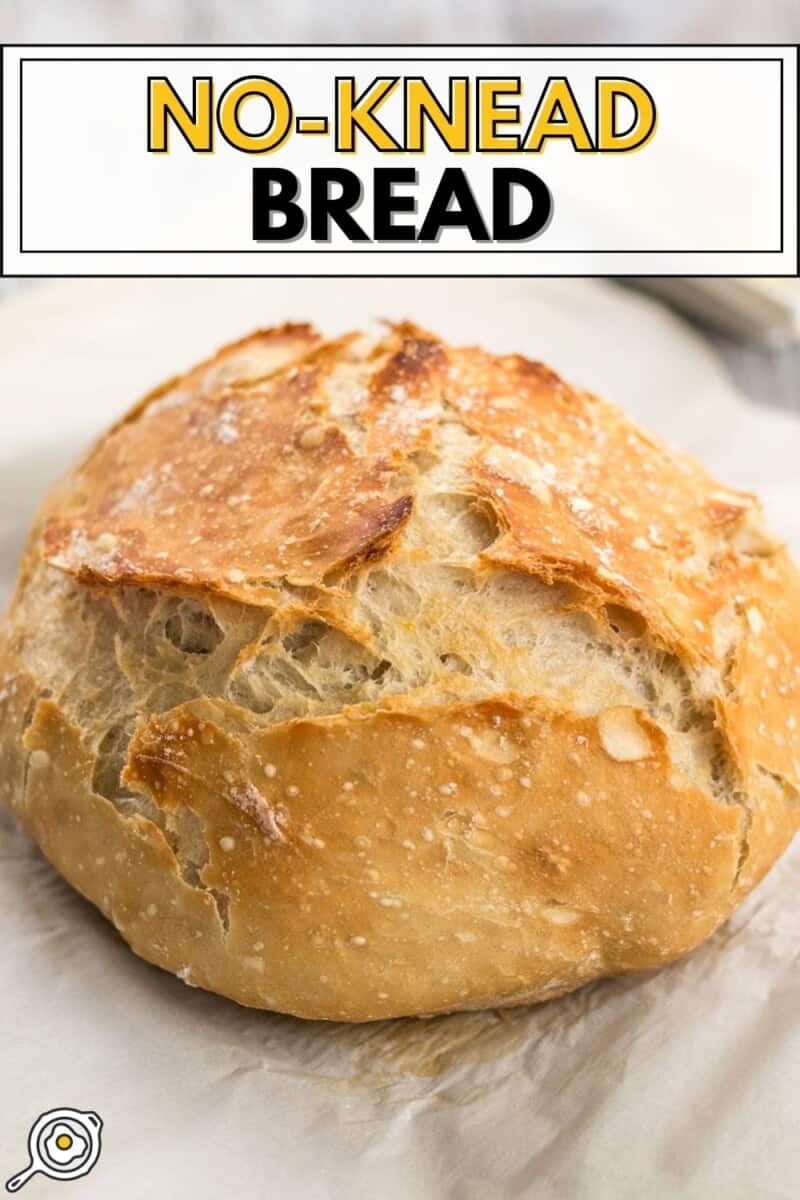 Side view of a loaf of no knead bread on parchment paper.