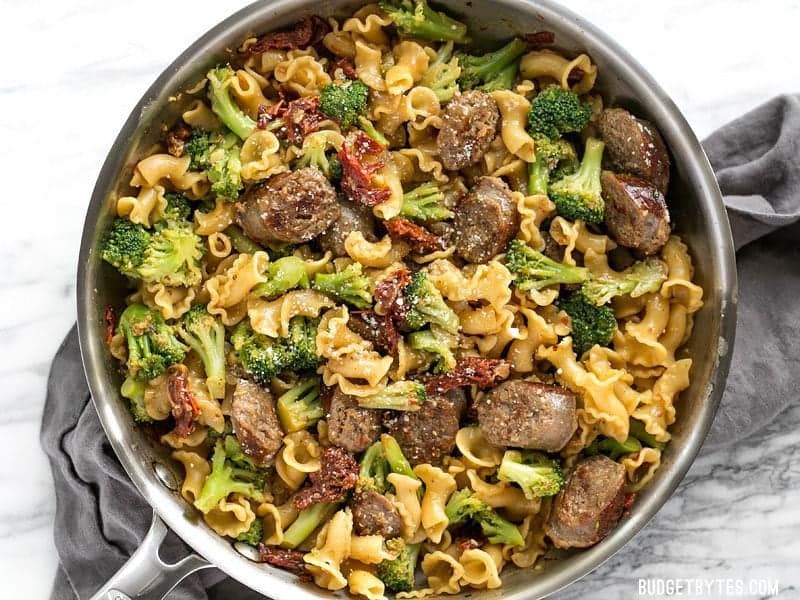 Overhead shot of One Pot Sausage and Sun Dried Tomato Pasta in the skillet with Parmesan sprinkled over top