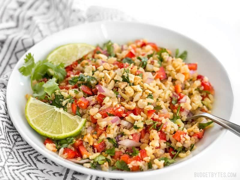 Riced cauliflower makes a filling low-carb base for this fresh and vibrant Thai-inspired Peanut Lime Cauliflower Salad. BudgetBytes.com Side view of a bowl of Peanut Lime Cauliflower Salad on a patterned napkin
