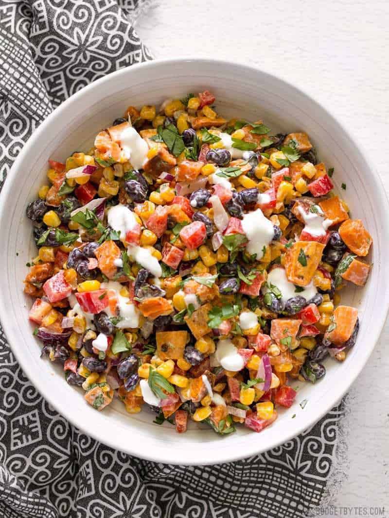 A big bowl of Roasted Sweet Potato Rainbow Salad with Lime Crema drizzled over top