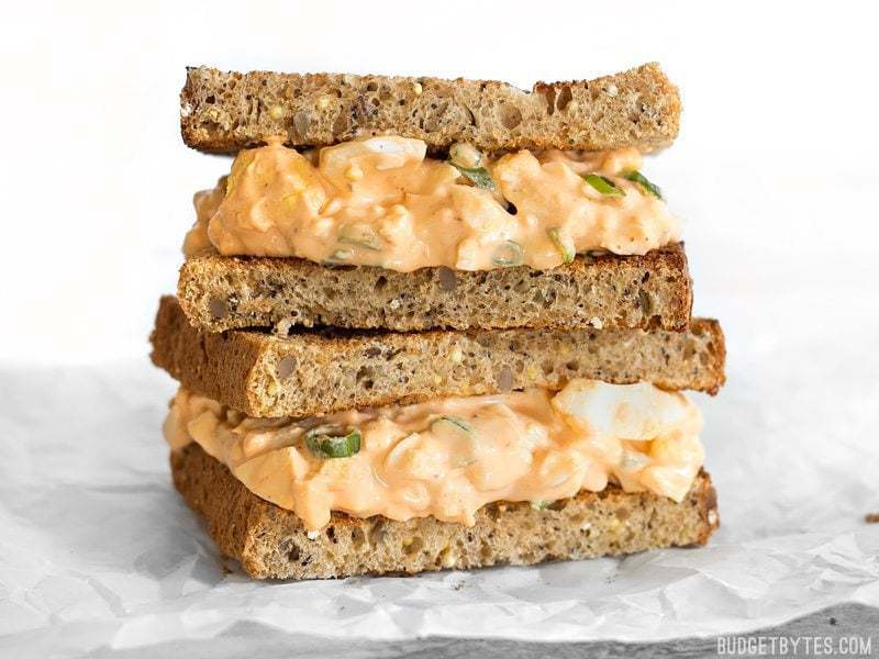 A Sriracha Egg Salad sandwich on wheat bread viewed from the side
