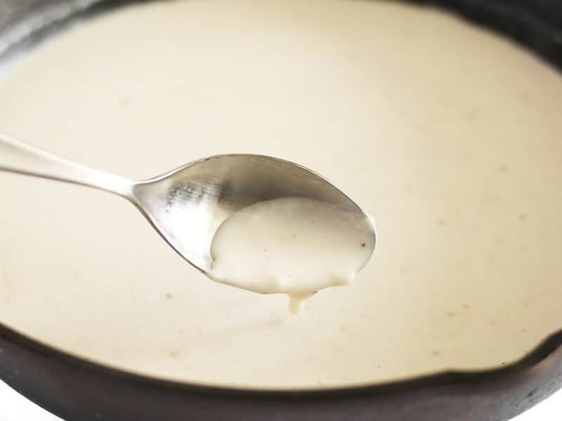 A spoon dipped into Thickened White Sauce