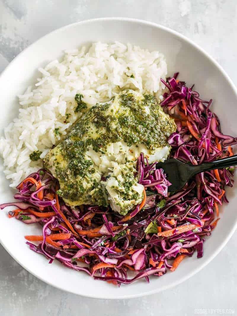 Baked Chimichurri Fish in a bowl served over rice and a red cabbage slaw