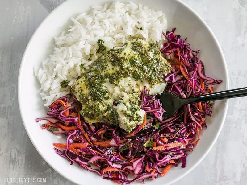 A Baked Chimichurri Fish Bowl being eaten with a black fork