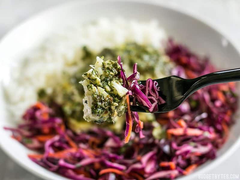 Close up of a forkful of baked chimichurri fish and slaw