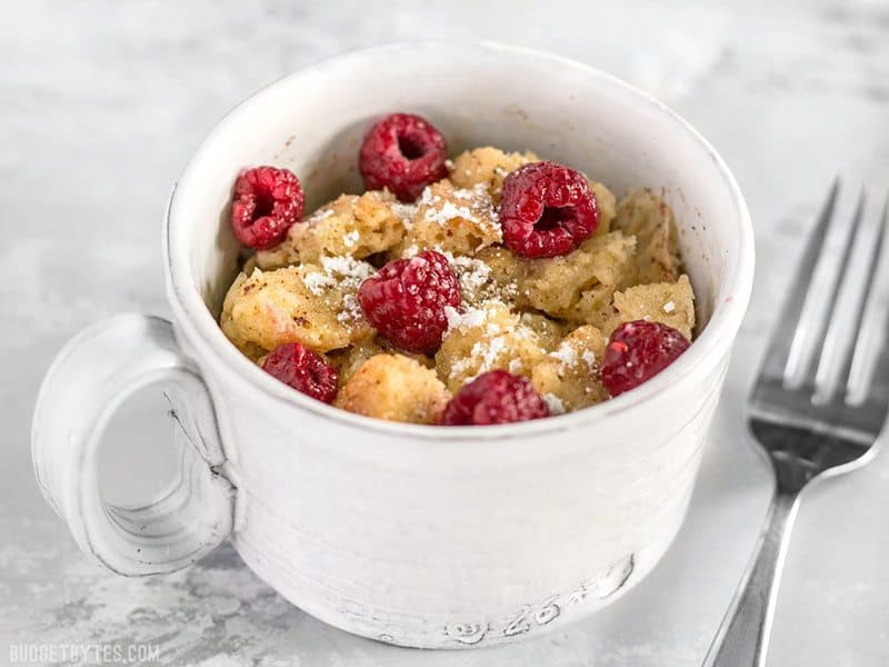 Front view of Microwave French Toast Mug topped with raspberries and powdered sugar