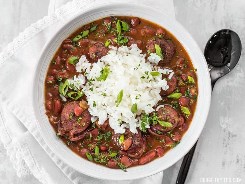 A big bowl of Pressure Cooker Red Beans topped with white rice, green onion, and parsley