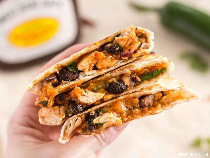 A hand holding a stack of Ultimate BBQ Chicken Quesadillas