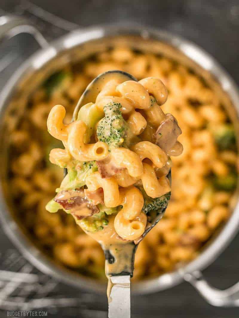 Close up of a spoonful of One Pot Bacon Broccoli Mac and Cheese with the pot in the background